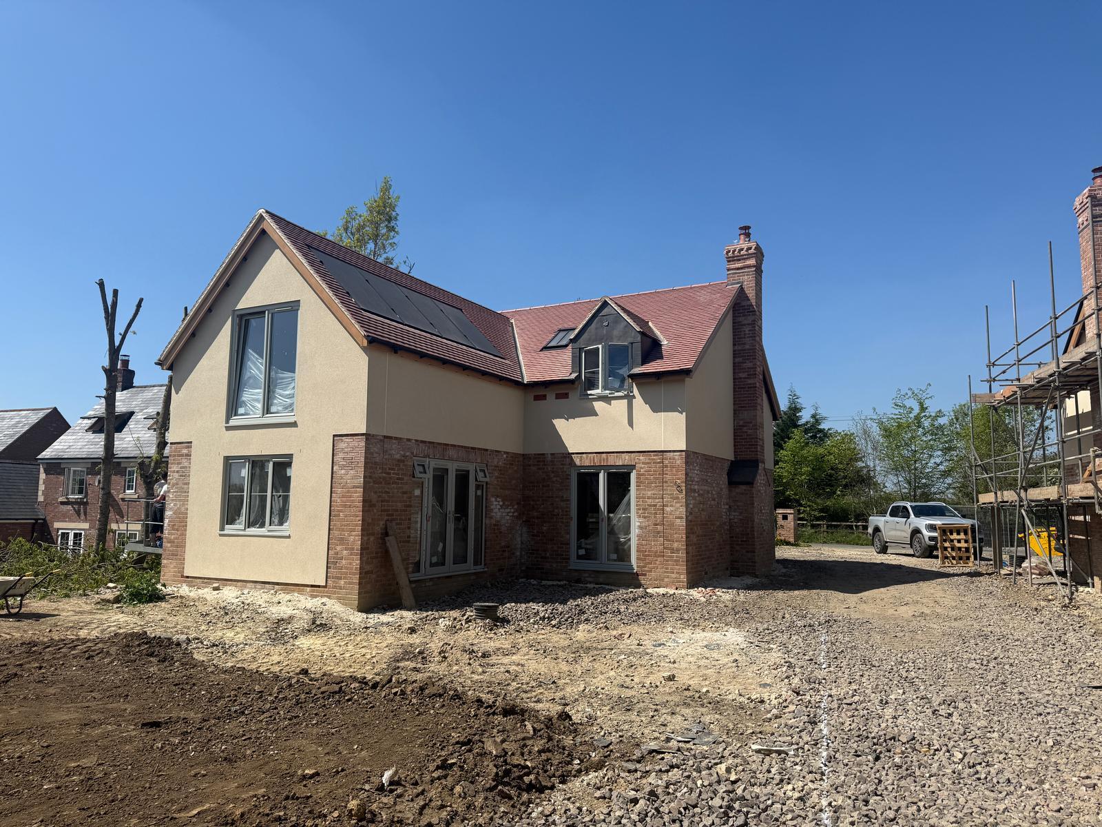 Detached new build property with render and brickwork, red tiled roof